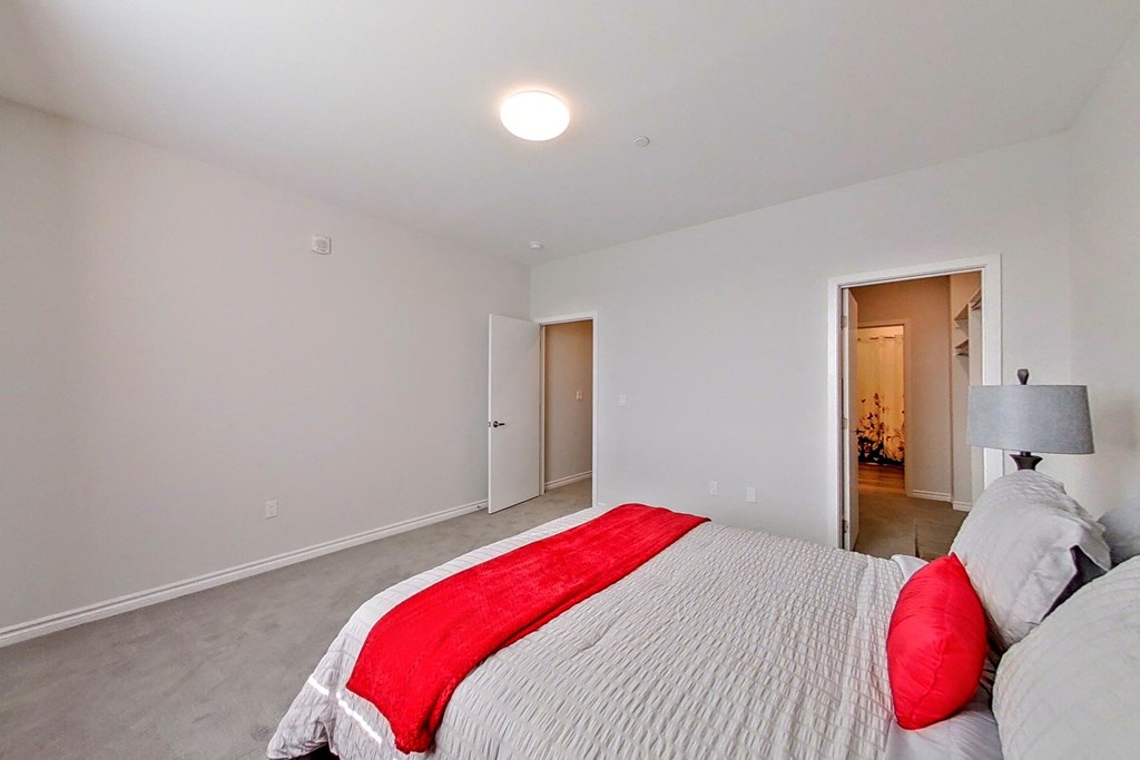 a bedroom with white walls and a red bed