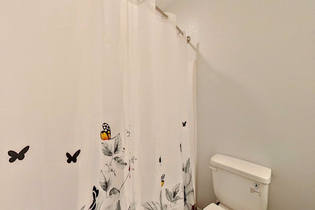 the bathroom has a shower curtain with butterflies on it