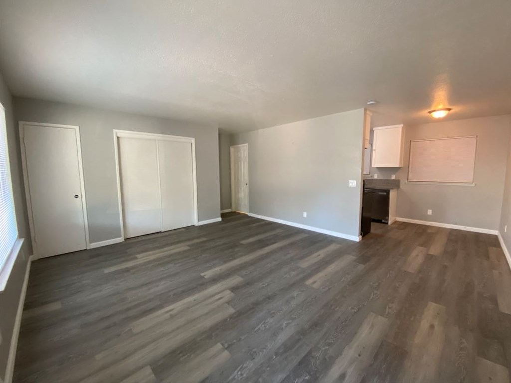 an empty living room with wooden floors and white walls