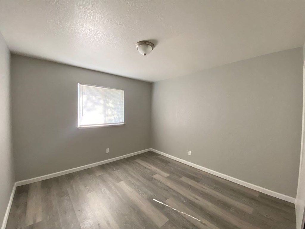 an empty room with wood floors and a window