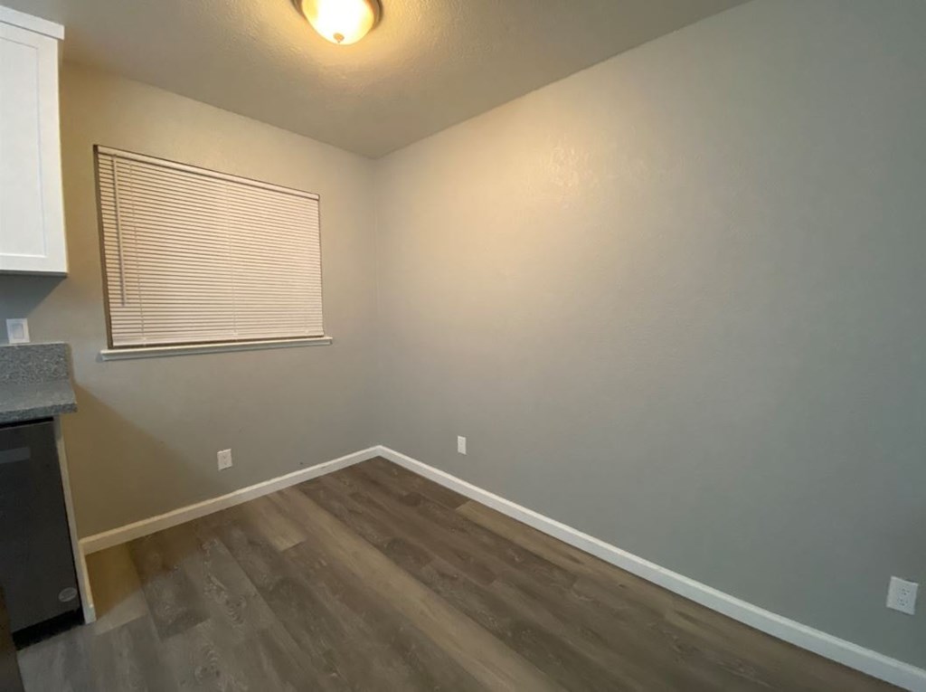 A room with wooden flooring and a window with blinds.
