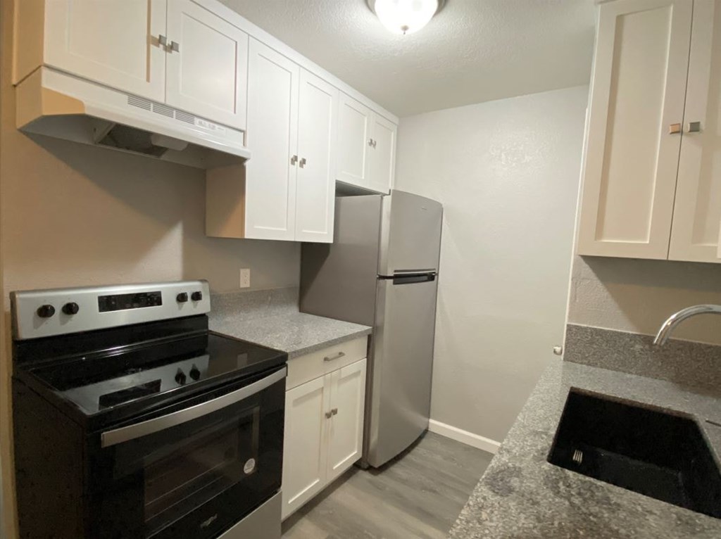 A kitchen with a stove, refrigerator, and cabinets.