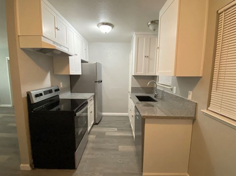 A kitchen with black appliances and beige cabinets.