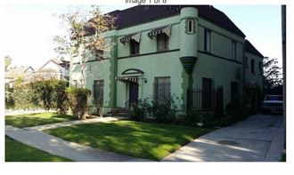 a green house with a sidewalk in front of it
