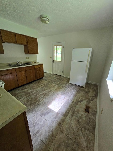 an empty kitchen with a refrigerator and a sink