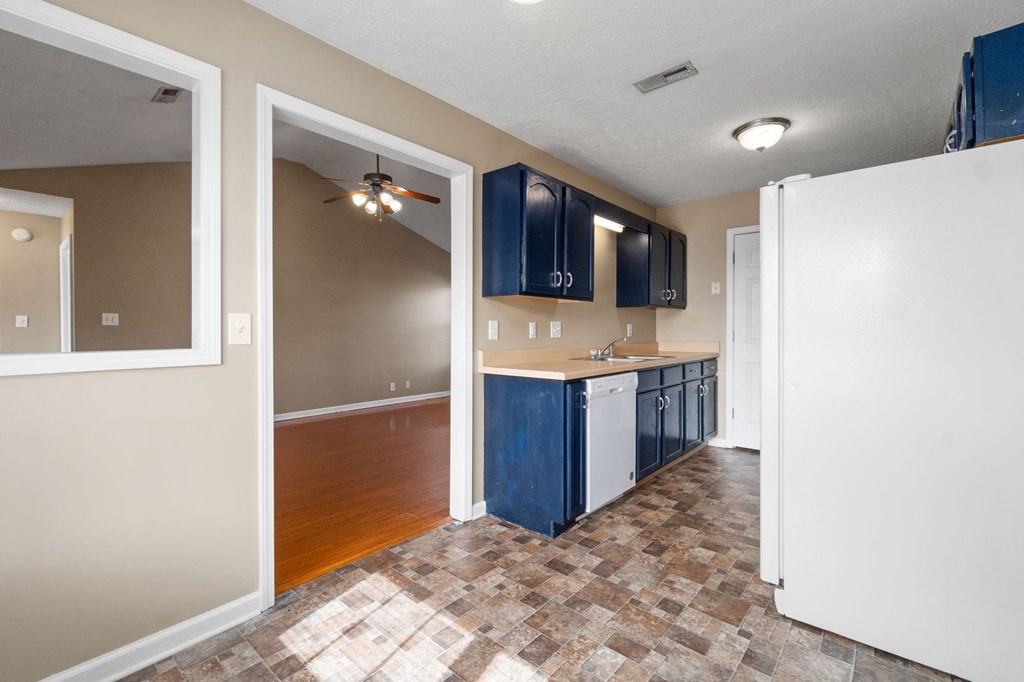 an empty kitchen with blue cabinets and a white refrigerator