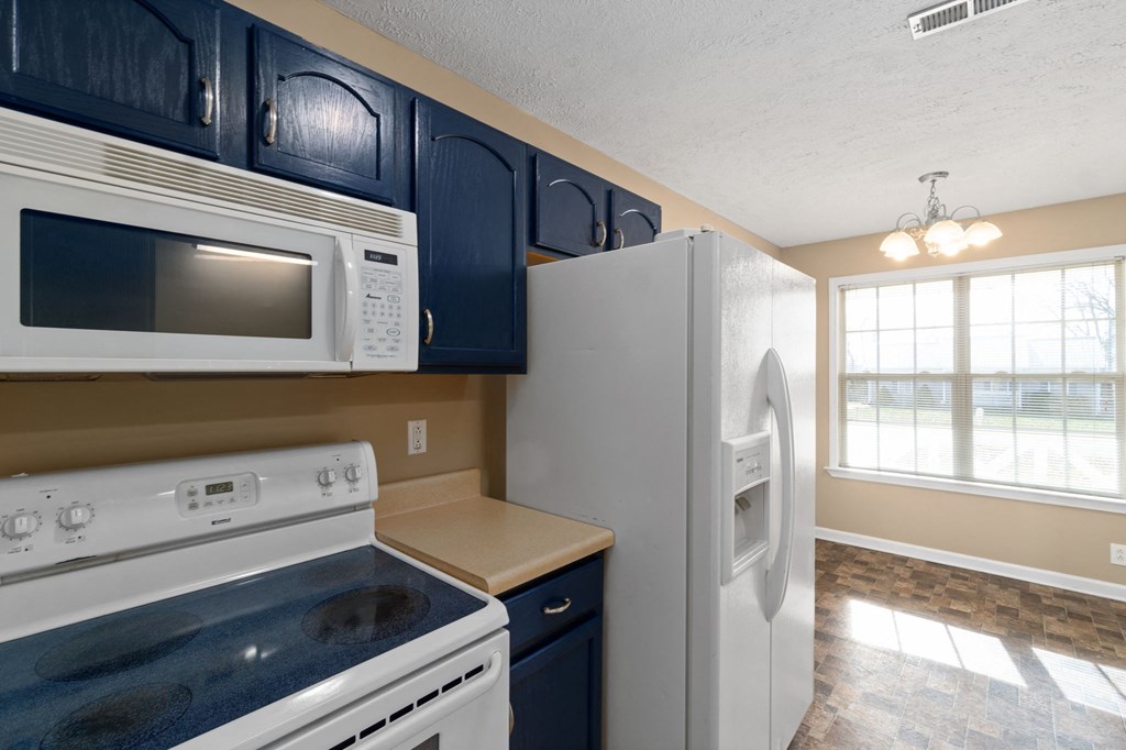 a kitchen with a stove refrigerator and microwave  and a window