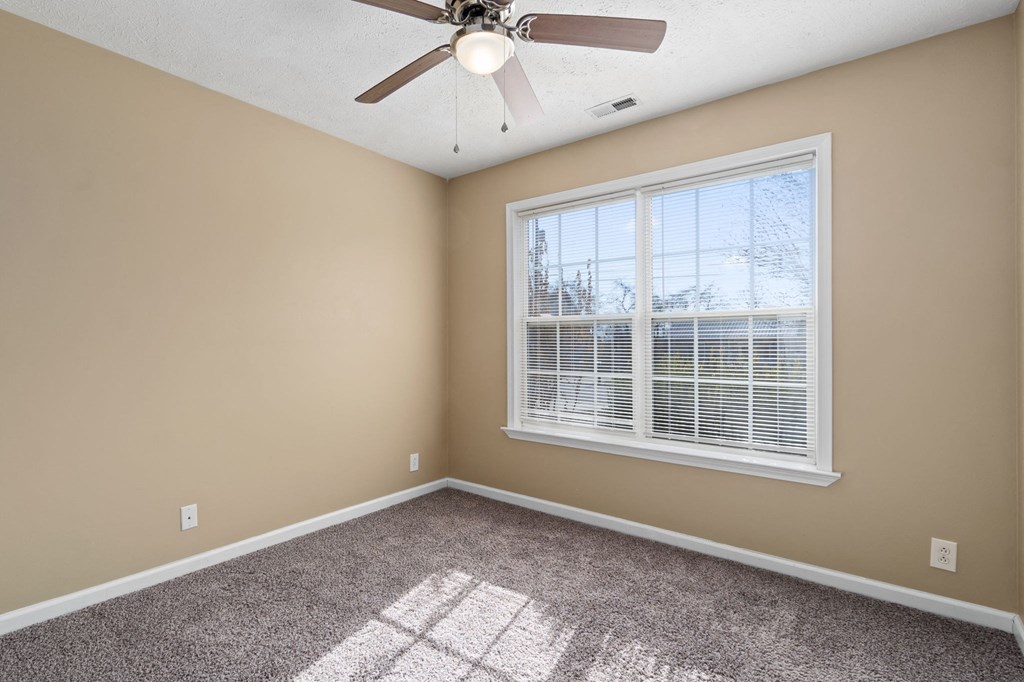 an empty bedroom with a large window and a ceiling fan