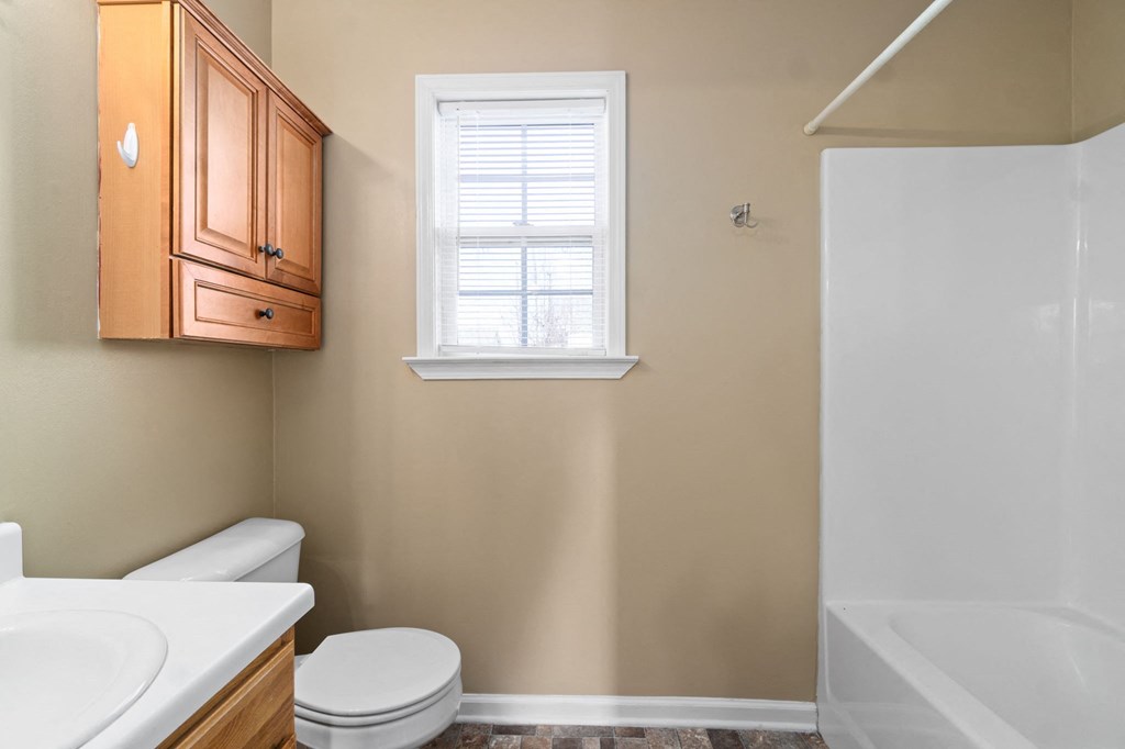 a bathroom with a toilet and a sink and a window