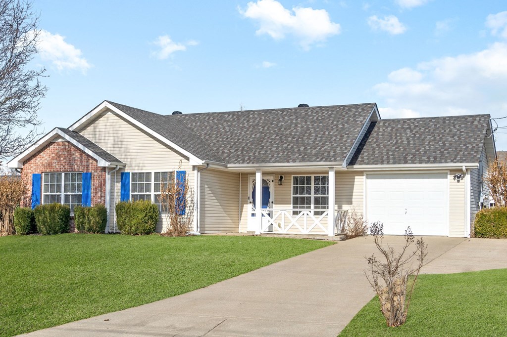 a tan house with a garage and a driveway