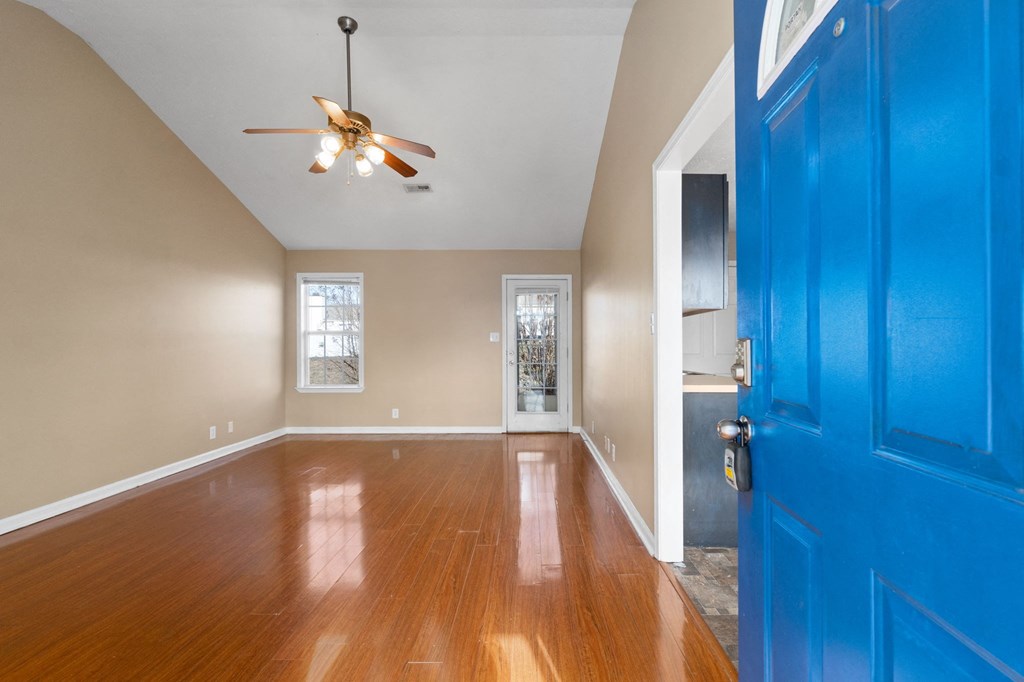 an empty living room with a blue door and a ceiling fan