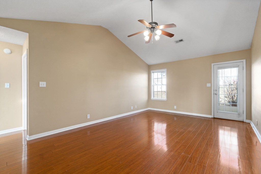 an empty living room with wood floors and a ceiling fan