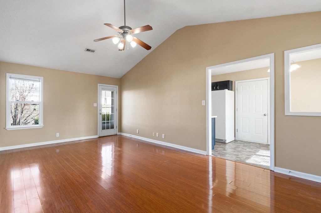 an empty living room with wood floors and a ceiling fan