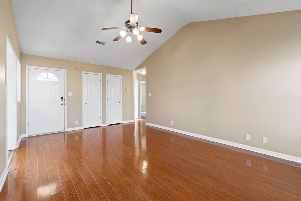 an empty living room with wood floors and a ceiling fan