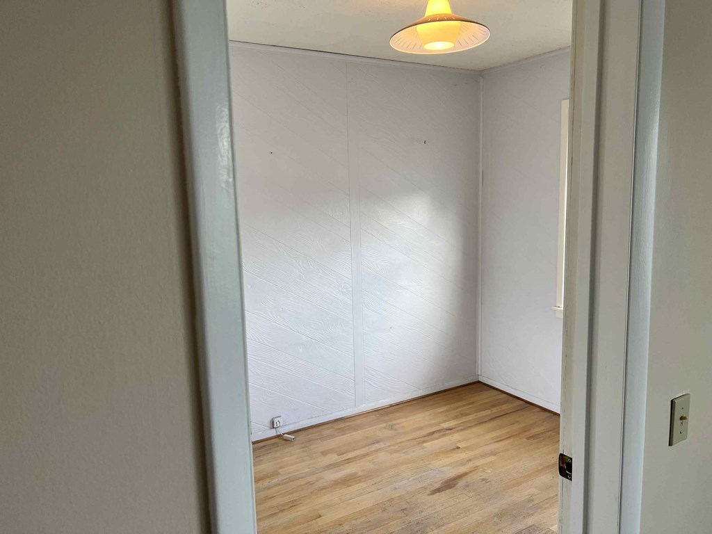 an empty room with a wood floor and a white wall