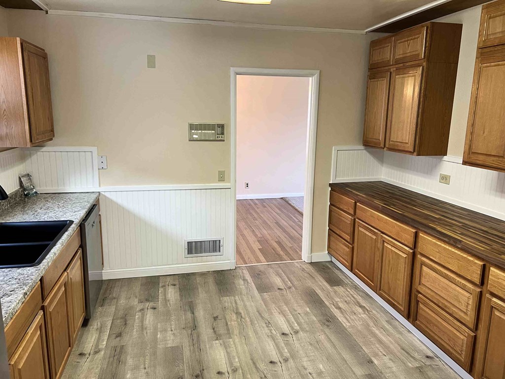 a kitchen with wooden cabinets and a door to a hallway
