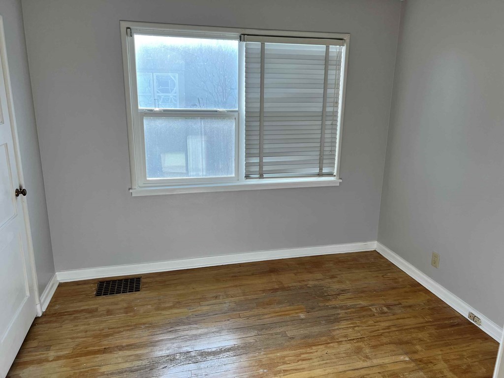 an empty room with a window and wooden floors