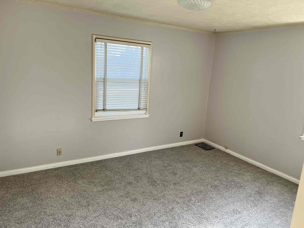 an empty room with a window and a carpet