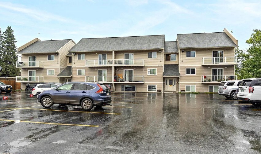 a parking lot with cars in front of an apartment building