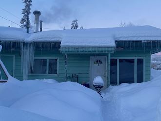 a house covered in snow with icicles on the roof