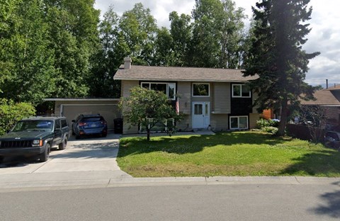 A house with a flag on the front porch and a car parked in the driveway.