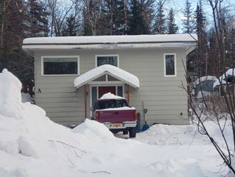 a house with a truck parked in front of it in the snow