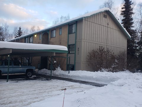 A building with a green truck parked in front of it.