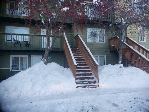 A large pile of snow in front of a building with a staircase.