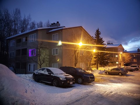 A black car is parked in a snow-covered parking lot.