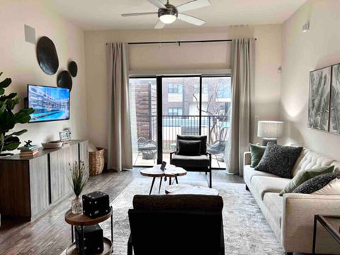 a living room with a couch and chairs and a ceiling fan