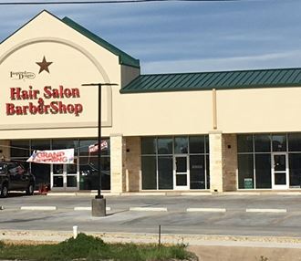 the front of a hair salon barber shop with a car parked outside