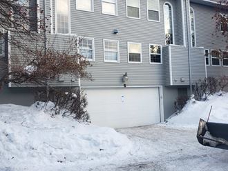a garage door in the snow in front of a house