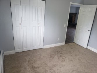 A room with two white doors and carpeted floor.