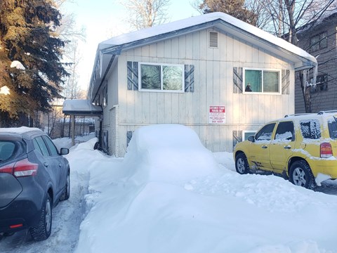 a house in the snow with cars parked in front of it