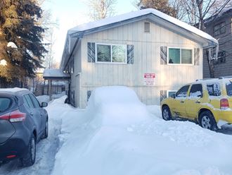 a house in the snow with cars parked in front of it