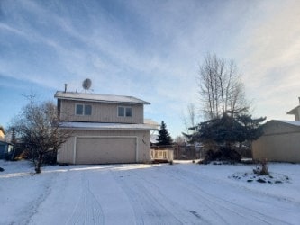 A house with a garage and a driveway covered in snow.