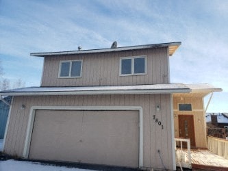 A two-story house with a garage door and a deck.