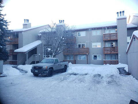 a truck parked in front of an apartment building in the snow