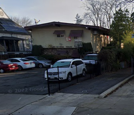 A white car is parked in front of a house.