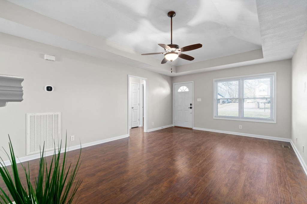 an empty living room with wood floors and a ceiling fan