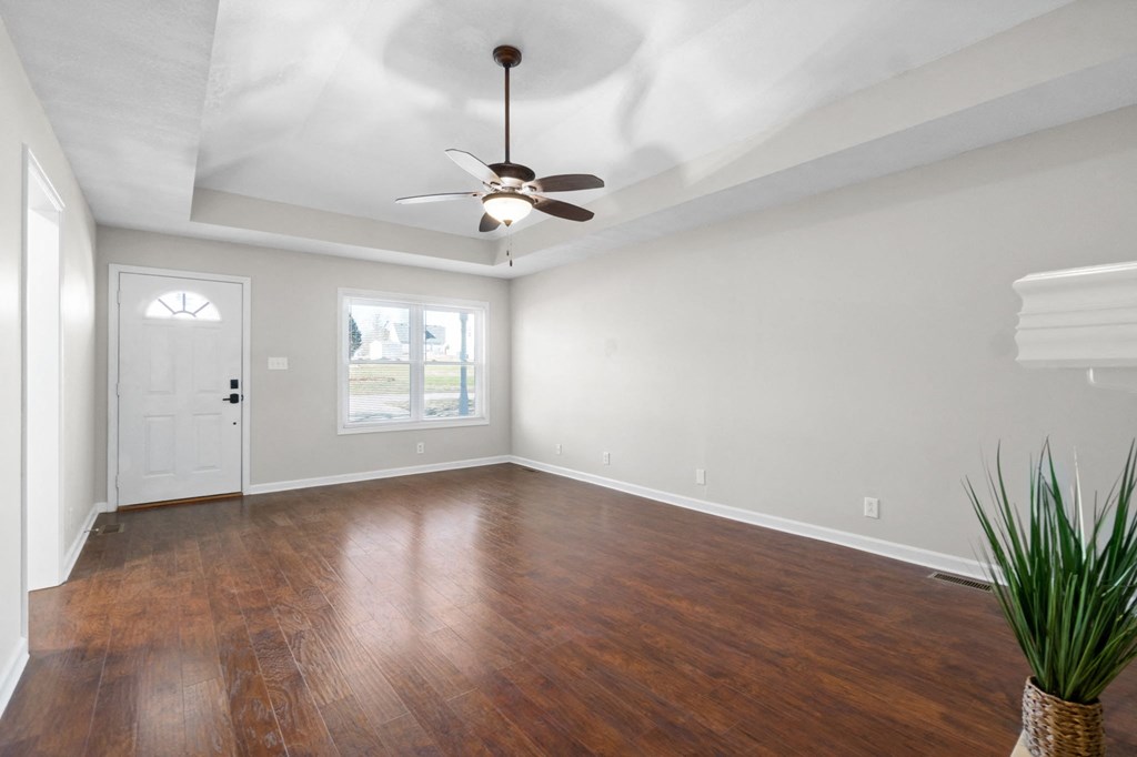 an empty living room with wood floors and a ceiling fan
