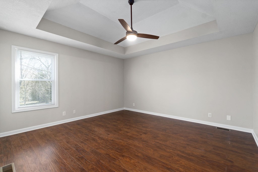 an empty living room with wood floors and a ceiling fan