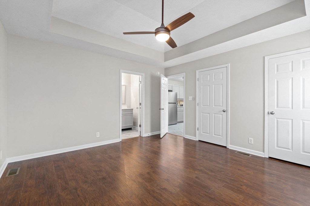 an empty living room with wood floors and a ceiling fan