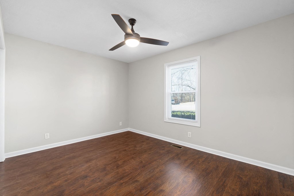 an empty living room with wood floors and a ceiling fan