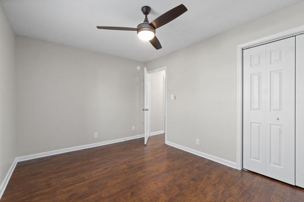 an empty living room with wood floors and a ceiling fan