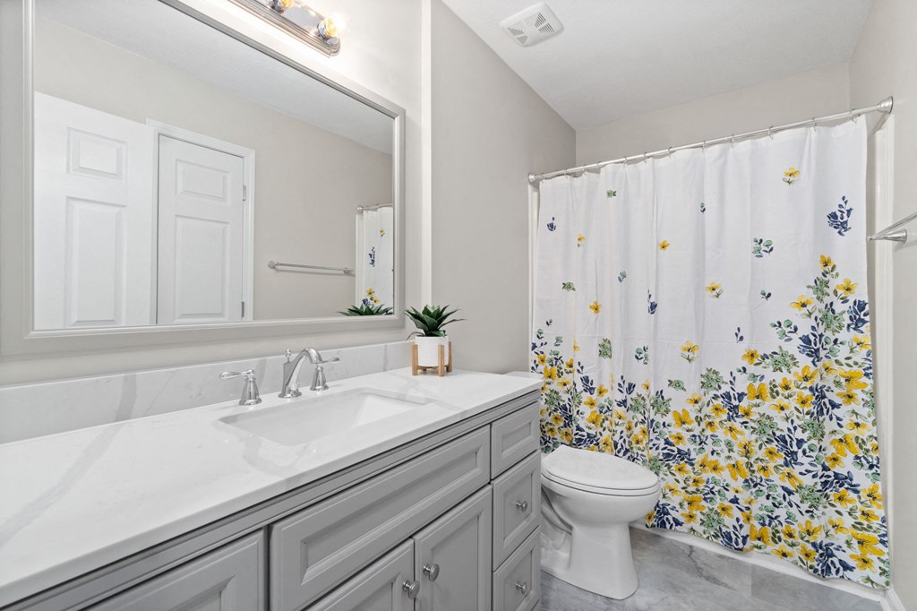 a white bathroom with a shower curtain and a toilet