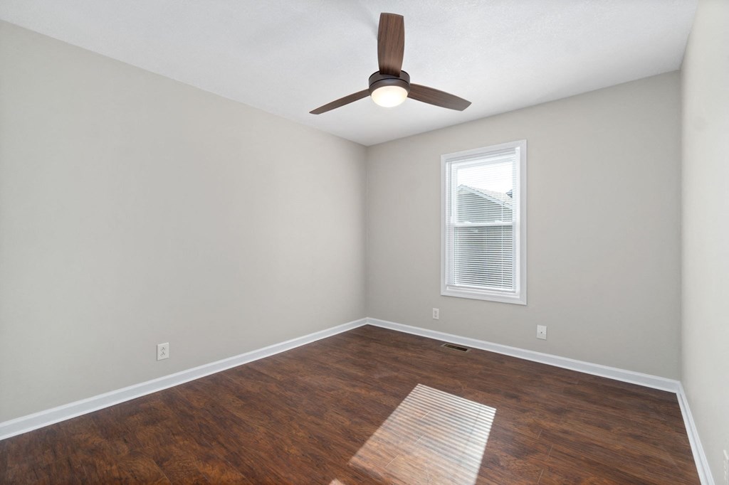 an empty living room with wood flooring and a ceiling fan