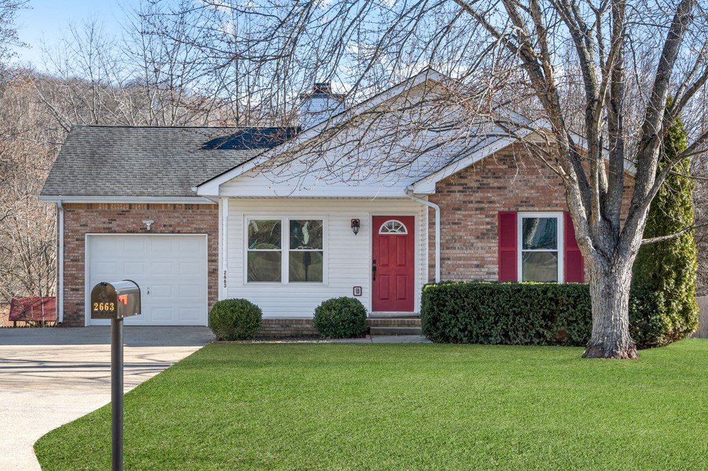 the front of a brick house with a red door and a lawn