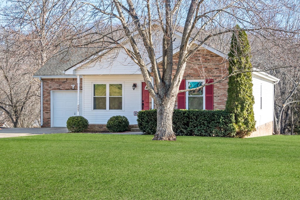 a small brick house with a tree in front of it