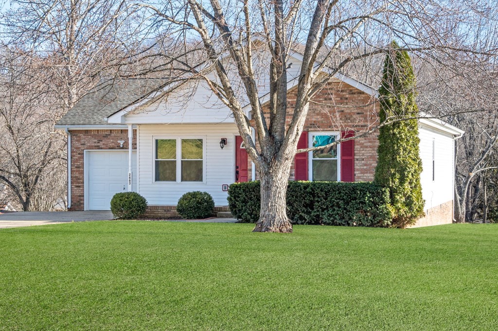 a small brick house with a tree in front of it